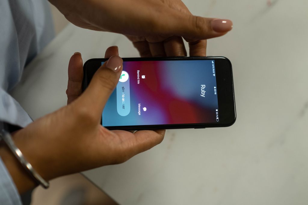 Vorbereitung Fotoshooting: In 5 Schritten zu unvergesslichen Bildern 2 Close-up image of hands holding a smartphone receiving a call from Ruby on a marble surface.